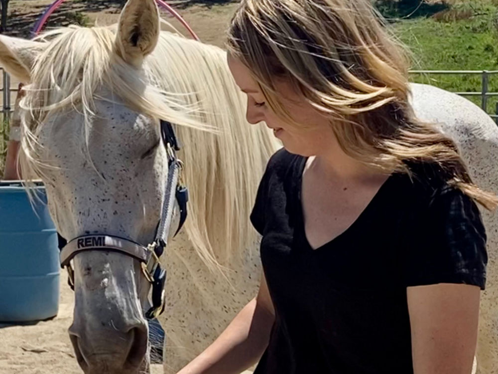 Woman with white horse at Warrior's Soul equine-assisted learning and horse riding lessons program.